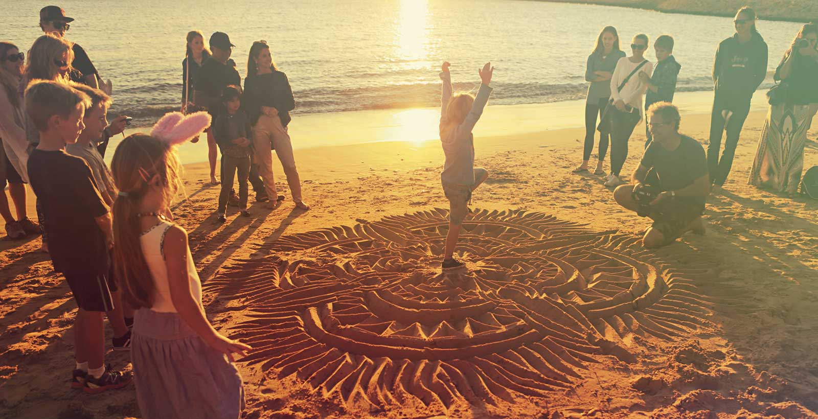 Beach calligrapher Child dancing on the beach at sunset in the middle of drawings on the beach
